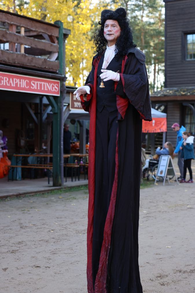 Große Stelzenfigur in Schwarz und Rot auf einem Festgelände